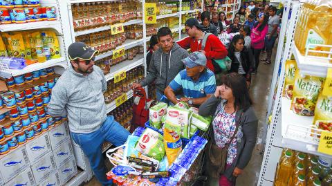 People queue in a supermarket in Valparaiso, Chile, on October 20, 2019. Fresh clashes broke out in Chile's capital Santiago on Sunday after two people died when a supermarket was torched overnight as violent protests sparked by anger over economic conditions and social inequality raged into a third day. (Photo by JAVIER TORRES / AFP)