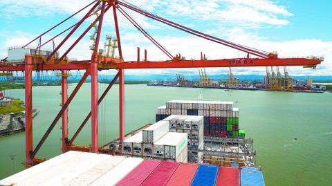 Buenaventura, Colombia - 11.28.22 Ultra large container ship have loading discharging operations in container terminal with gantry cranes. View of forward part and container terminal.