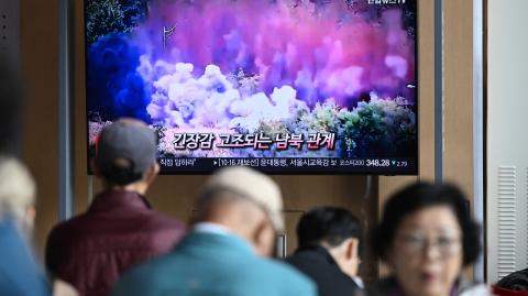 People watch a television screen showing a news broadcast with footage of an explosion on a road connecting North and South Korea on October 15, 2024, at a train station in Seoul on October 16, 2024. - North Korea blew up sections of the deeply symbolic roads and railways connecting it to the South on October 15, Seoul's military said, adding it had conducted a "counter-fire" operation in response. (Photo by Jung Yeon-je / AFP)