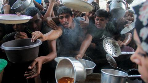 Palestinos se reúnen para recibir comida preparada por una cocina benéfica, en medio del conflicto entre Israel y Hamás.