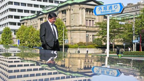 A man walks past the Bank of Japan (BOJ) building in Tokyo, in this October 30, 2015 file photo. Japan's central bank, which dominates the domestic bond market, has begun to call the shots in the equity market as well -- to the point where asset managers are looking to design investment funds with the Bank of Japan in mind.     REUTERS/Thomas Peter/Files