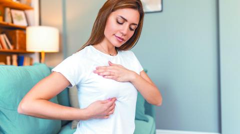 Young Caucasian woman palpating her breast by herself that she concern about breast cancer. Healthcare and breast cancer concept