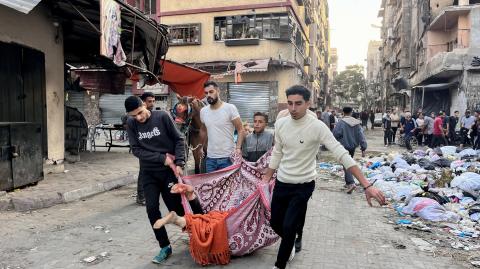 Hombres llevan un cuerpo dentro de una manta en Beit Lahia, en el norte de la Franja de Gaza