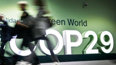 La gente pasa junto al logotipo de la Conferencia de las Naciones Unidas sobre el Cambio Climático de 2024 (COP29) en Bakú.