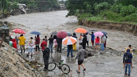 Personas damnificadas observan un arroyo inundado cerca de San Pedro Sula, Honduras.