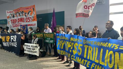 Activistas con pancartas y banderas celebran una reunión para exigir que los países ricos ayuden a las naciones en desarrollo a abordar el calentamiento global.