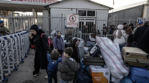 Los refugiados sirios que viven en Turquía esperan en una fila con sus pertenencias en la puerta fronteriza de Cilvegozu antes de ingresar a Siria por el distrito de Reyhanli