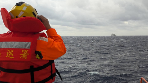 Esta fotografía tomada entre el 7 y 8 de diciembre de 2024 y publicada el 9 de diciembre por la Guardia Costera de Taiwán muestra a un miembro de la tripulación a bordo de un barco de la Guardia Costera de Taiwán monitoreando un barco de la guardia costera china en aguas al este de Taiwán.