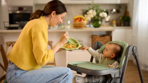 Mother spoon feeding her baby boy in the kitchen