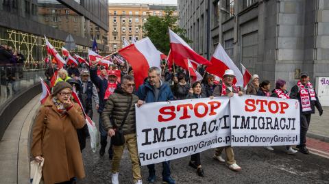 La gente sostiene una pancarta antiinmigración mientras participa en la protesta.
