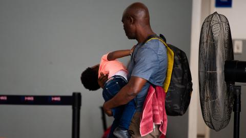 Un hombre carga a un niño a su llegada a la terminal Guy Malary, utilizada para vuelos nacionales, del Aeropuerto Internacional Toussaint Louverture de Puerto Príncipe, Haití.