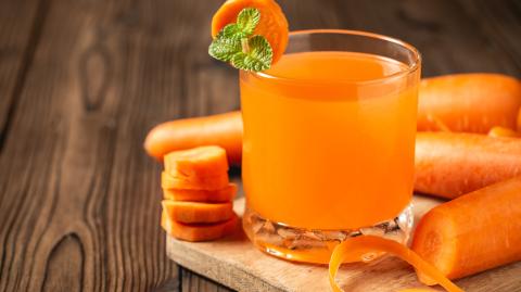 Carrot juice in glass on wooden table.