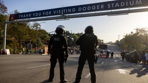 Agentes de policía montan guardia mientras cierran la puerta principal del Dodger Stadium ante presencia de manifestantes.