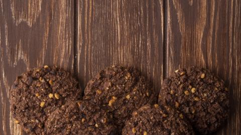 top view of chocolate chip cookies with cereals nuts and cocoa on wooden background with copy space