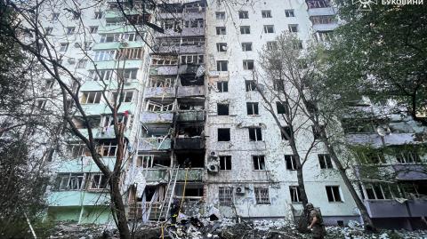 Bomberos y un policía trabajan en el lugar de un edificio de apartamentos dañado por ataques con drones y misiles rusos.