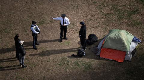 La Policía del Parque habla con un hombre que se negó a irse después de que miembros del Servicio de Parques Nacionales de EE. UU. desalojaran un campamento de personas sin hogar.