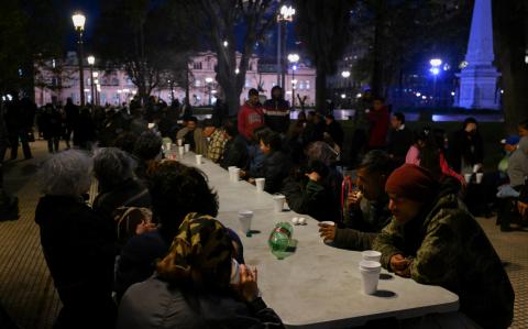 Personas comen alimentos proporcionados por la organización Red Solidaria en la Plaza de Mayo, frente al palacio presidencial de Casa Rosada en Buenos Aires, capital argentina.