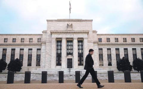 FILE PHOTO: A man walks past the Federal Reserve in Washington, December 16, 2015. The U.S. central bank is widely expected on Wednesday to hike its key federal funds rate by a modest 0.25 percent. It would be the first tightening in more than nine years and a big step on the tricky path of returning monetary policy to a more normal footing after aggressive bond-buying and near-zero borrowing costs. REUTERS/Kevin Lamarque/File Photo