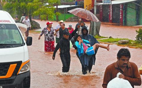 People walk on a flooded street after the hit of Hurricane John in Acapulco, Mexico, on September 26, 2024. - Hurricane John, which made landfall in Mexico on September 23, leaving at least five dead, re-formed as a cyclone early September 26, and is expected to hit the country again, authorities said. (Photo by Francisco Robles / AFP)