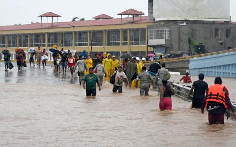 People walk on a flooded street heading to a shelter following Hurricane John in Acapulco, Guerrero State, Mexico, on September 27, 2024. Mexican troops scrambled Friday to help victims of a hurricane that battered the Pacific coast, including the beach resort of Acapulco, which is still recovering from a devastating storm last year. (Photo by Francisco ROBLES / AFP)