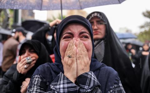 Una mujer reacciona mientras está bajo la lluvia con otros manifestantes