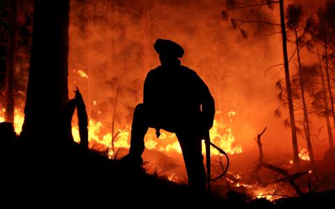 Un hombre trabaja para extinguir un incendio forestal en Intiyaco, en la provincia de Córdoba, Argentina.