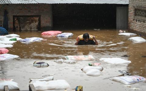 Un hombre trata de sacar sus cosas mientras va por el agua.