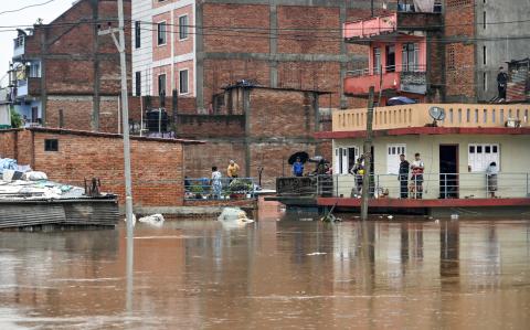 Los residentes se encuentran en el piso superior de sus casas mientras inspeccionan las aguas de las inundaciones después de que el río Bagmati se desbordara durante las lluvias monzónicas.