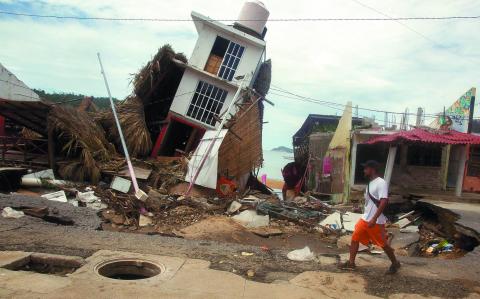 A man walks near a damaged building after the passing of Tropical Storm John, in Puerto Marques, Guerrero state, Mexico September 29, 2024. REUTERS/Javier Verdin