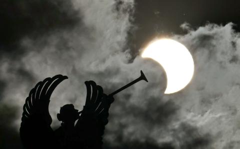 Partial view of the solar annular eclipse is pictured behind an Angels monument at the National Congress building in Buenos Aires, taken on October 2, 2024. - Part of the southern hemisphere will witness this Wednesday an annular eclipse that will occur when the Moon almost totally covers the Sun, leaving a luminous ring visible, a spectacle that will be seen in its maximum splendor from the Chilean and Argentinean Patagonia. (Photo by Luis ROBAYO / AFP)