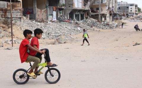 Children ride a bicycle across a war-devastated street in Gaza City on October 2, 2024, amid the ongoing war between Israel and the Palestinian Hamas militant group. (Photo by Omar AL-QATTAA / AFP)