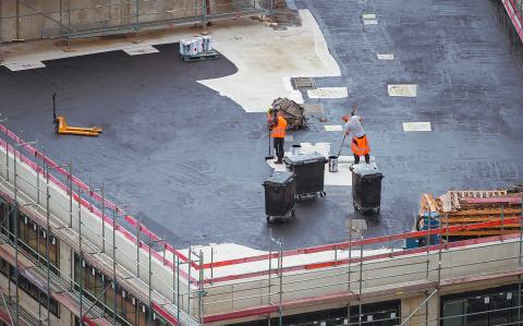 Roofer painting flat roof of a commercial building.