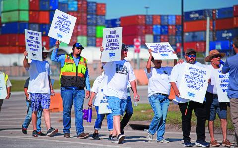 Striking workers hold up signs and march in front of the Bayport Container Terminal in Seabrook, Texas, on October 3, 2024. - The International Longshoremen's Association (ILA), 85,000 members strong, has launched its first strike since 1977 after weeks of deadlocked negotiations over a six-year labor agreement. (Photo by Mark Felix / AFP)