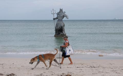 Una mujer pasa junto a una estatua de Poseidón mientras avanza el huracán Milton, en Progreso, 7 de octubre de 2024.