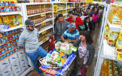 People queue in a supermarket in Valparaiso, Chile, on October 20, 2019. Fresh clashes broke out in Chile's capital Santiago on Sunday after two people died when a supermarket was torched overnight as violent protests sparked by anger over economic conditions and social inequality raged into a third day. (Photo by JAVIER TORRES / AFP)