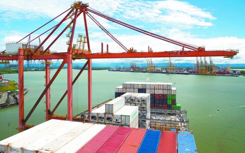 Buenaventura, Colombia - 11.28.22 Ultra large container ship have loading discharging operations in container terminal with gantry cranes. View of forward part and container terminal.