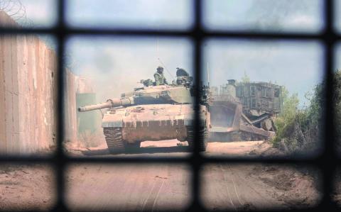 PHOTO TAKEN DURING A CONTROLLED EMBED TOUR WITH THE ISRAELI ARMY AND SUBSEQUENTLY EDITED UNDER MILITARY SUPERVISION -- This picture taken on October 13, 2024 shows an Israeli battle tank entering Lebanon from northern Israel at the southern Lebanese border point of Naqoura. - UN peacekeepers in Lebanon said Israeli tanks broke through a gate to enter a Blue Helmet position in Lebanon on October 13, after blocking their movement the previous day. (Photo by Menahem KAHANA / AFP)