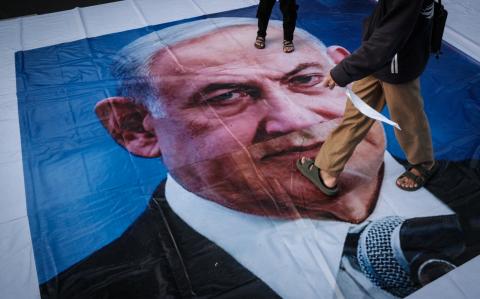 A demonstrator walks on a banner with a portrait of Israel's Prime Minister Benjamin Netanyahu during a pro-Palestinian rally on the eve of the first anniversary of the Israel-Hamas conflict, in Jakarta on October 6, 2024. (Photo by Yasuyoshi CHIBA / AFP)