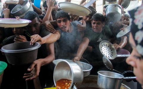 Palestinos se reúnen para recibir comida preparada por una cocina benéfica, en medio del conflicto entre Israel y Hamás.