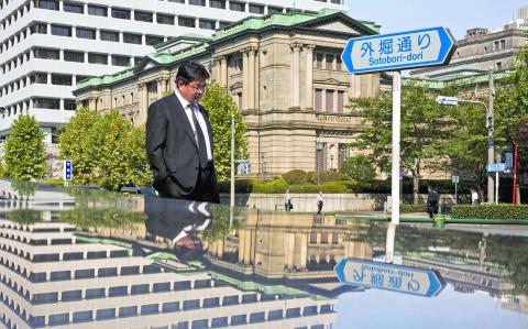 A man walks past the Bank of Japan (BOJ) building in Tokyo, in this October 30, 2015 file photo. Japan's central bank, which dominates the domestic bond market, has begun to call the shots in the equity market as well -- to the point where asset managers are looking to design investment funds with the Bank of Japan in mind.     REUTERS/Thomas Peter/Files