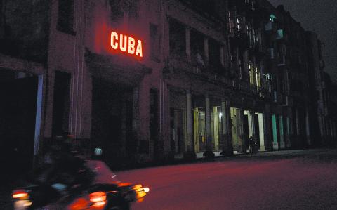 A sign lits a blacked out street during the second day of the nationwide blackout in Havana October 19, 2024. - Hurricane Oscar is due to hit the island of Cuba imminently, with the risk of further affecting the population, who are spending their second night without electricity due to a giant blackout. (Photo by ADALBERTO ROQUE / AFP)