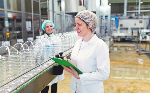 Female workers in bottling factory checking water bottles before shipment. Inspection quality control.