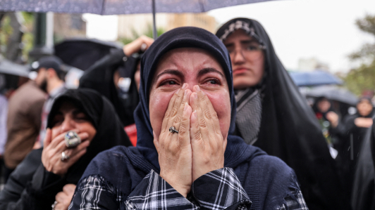 Una mujer reacciona mientras está bajo la lluvia con otros manifestantes