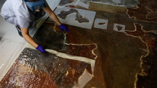 Un técnico de conservación y restauración retira la emulsión de disolvente gelificado durante el proceso de biolimpieza de un panel con una pintura mural retirada de la iglesia de Santos Juanes.