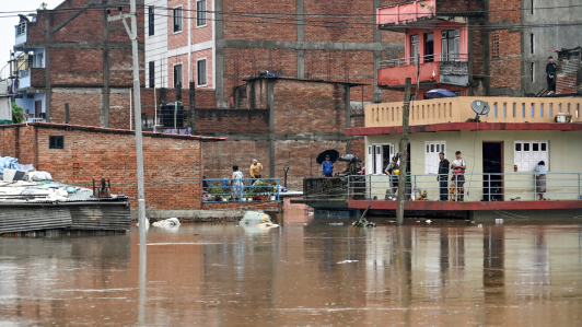 Los residentes se encuentran en el piso superior de sus casas mientras inspeccionan las aguas de las inundaciones después de que el río Bagmati se desbordara durante las lluvias monzónicas.