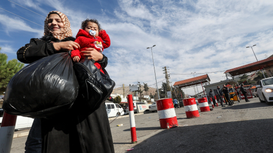 Una mujer lleva a un niño en el cruce fronterizo de Masnaa después de que los rebeldes sirios anunciaran que habían derrocado al presidente Bashar al-Assad.