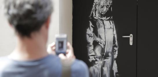 Un hombre toma una fotografía de una obra de arte reciente del artista callejero Banksy en París en una calle lateral de la sala de conciertos Bataclan donde un ataque terrorista mató a 90 personas el 13 de noviembre de 2015. 