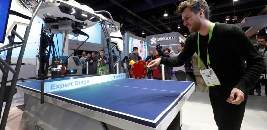 Jacobs Otto de los Países Bajos juega un juego con "Forpheus", un tutor de ping pong robótico equipado con AI en el stand de Omron.