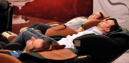 Los asistentes prueban los sillones de masaje en el stand de Homedics.