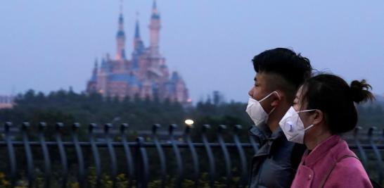 Visitors wearing masks walk past Shanghai Disney Resort, that will be closed during the Chinese Lunar New Year holiday following the outbreak of a new coronavirus, in Shanghai